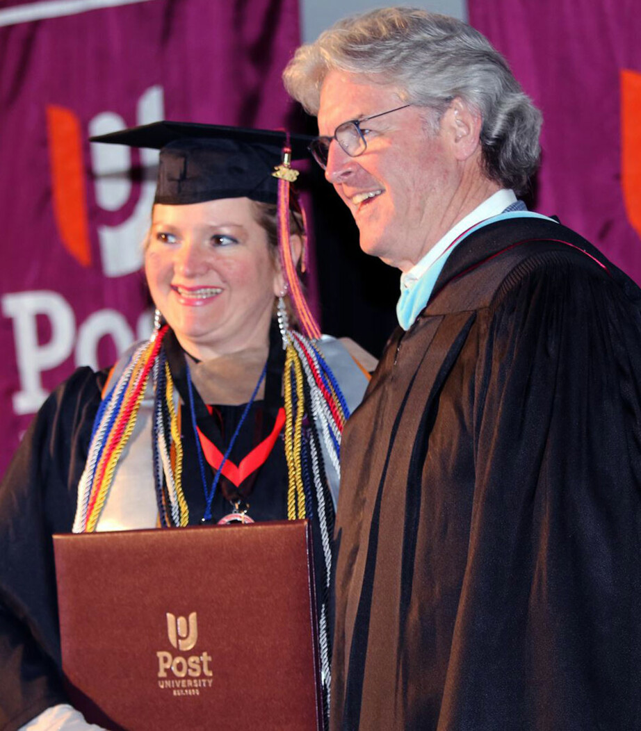 President of Post University John Hopkins stands smiling with a woman at graduation