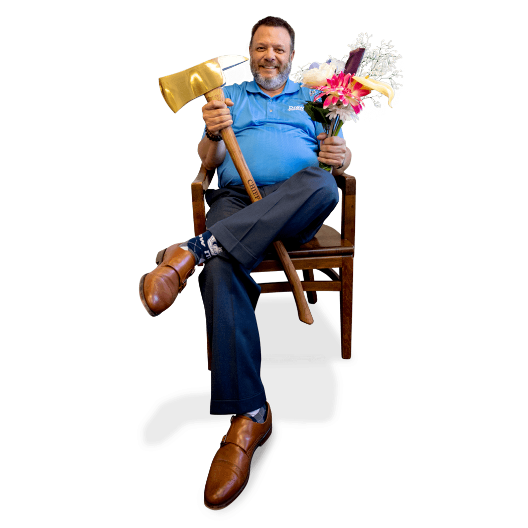 Frank Monteiro of Waterbury CT sits in chair smiling, holding a brass axe and bouquet of flowers