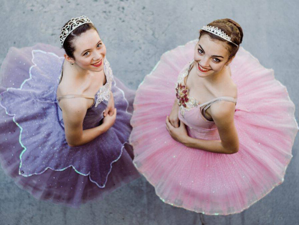 Two female ballet dancers in pink and purple tutus looking up