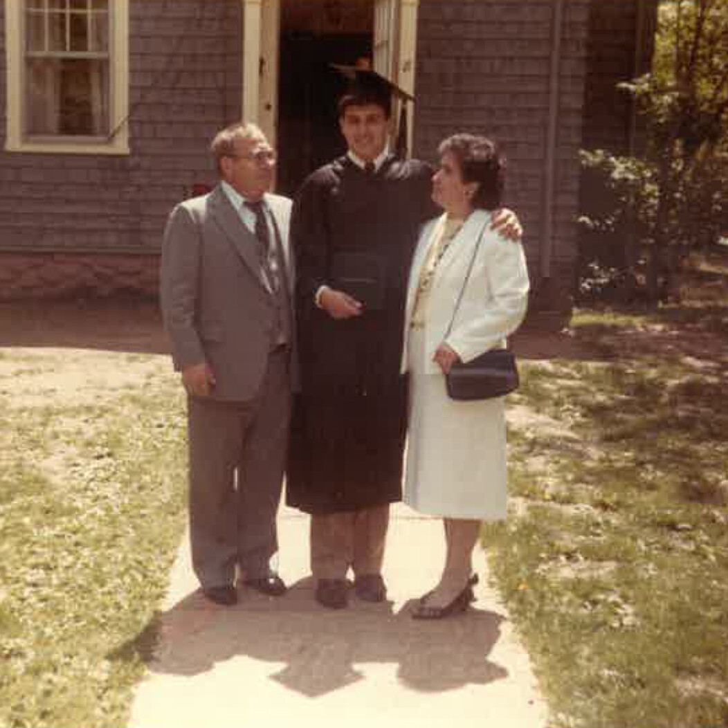 Older photo of Frank Tavera of Waterbury CT standing with parents after graduating from UConn graduation