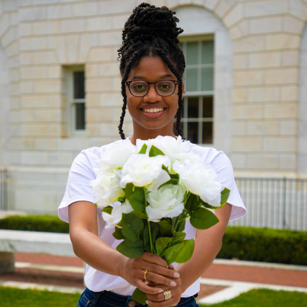 Waterbury woman smiling and holding a bunch of white flowers in front of her