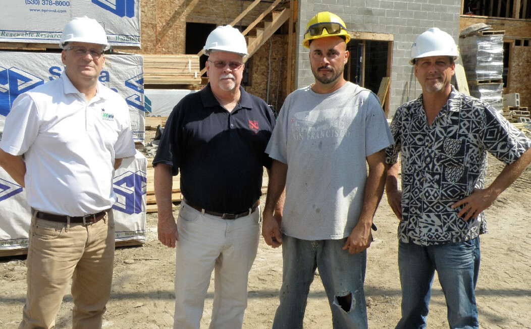 Four Waterbury CT men standing at a construction site and wearing white and yellow hard hats