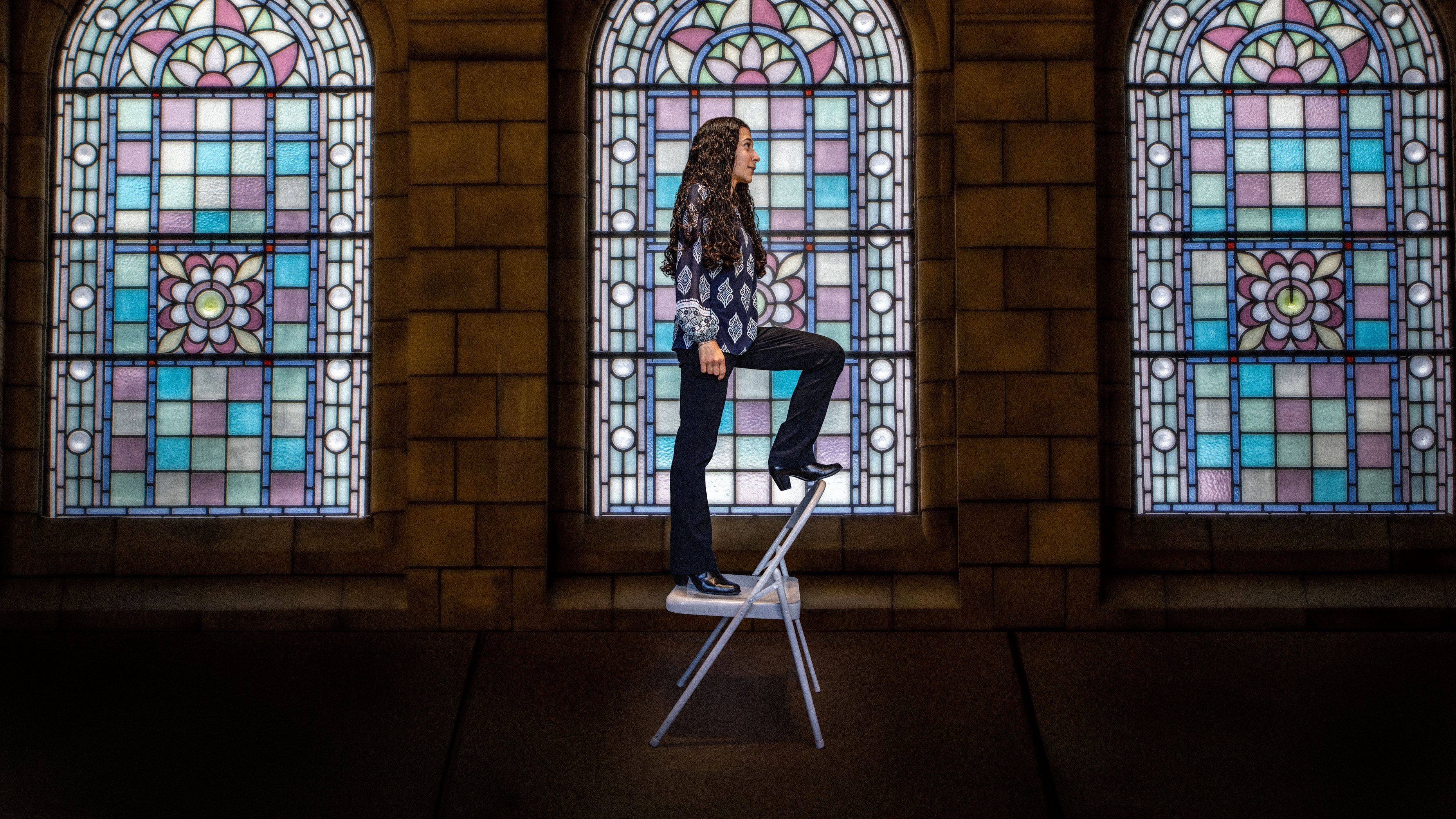 Waterbury, CT native Celina Caetano on a metal chair inside a church