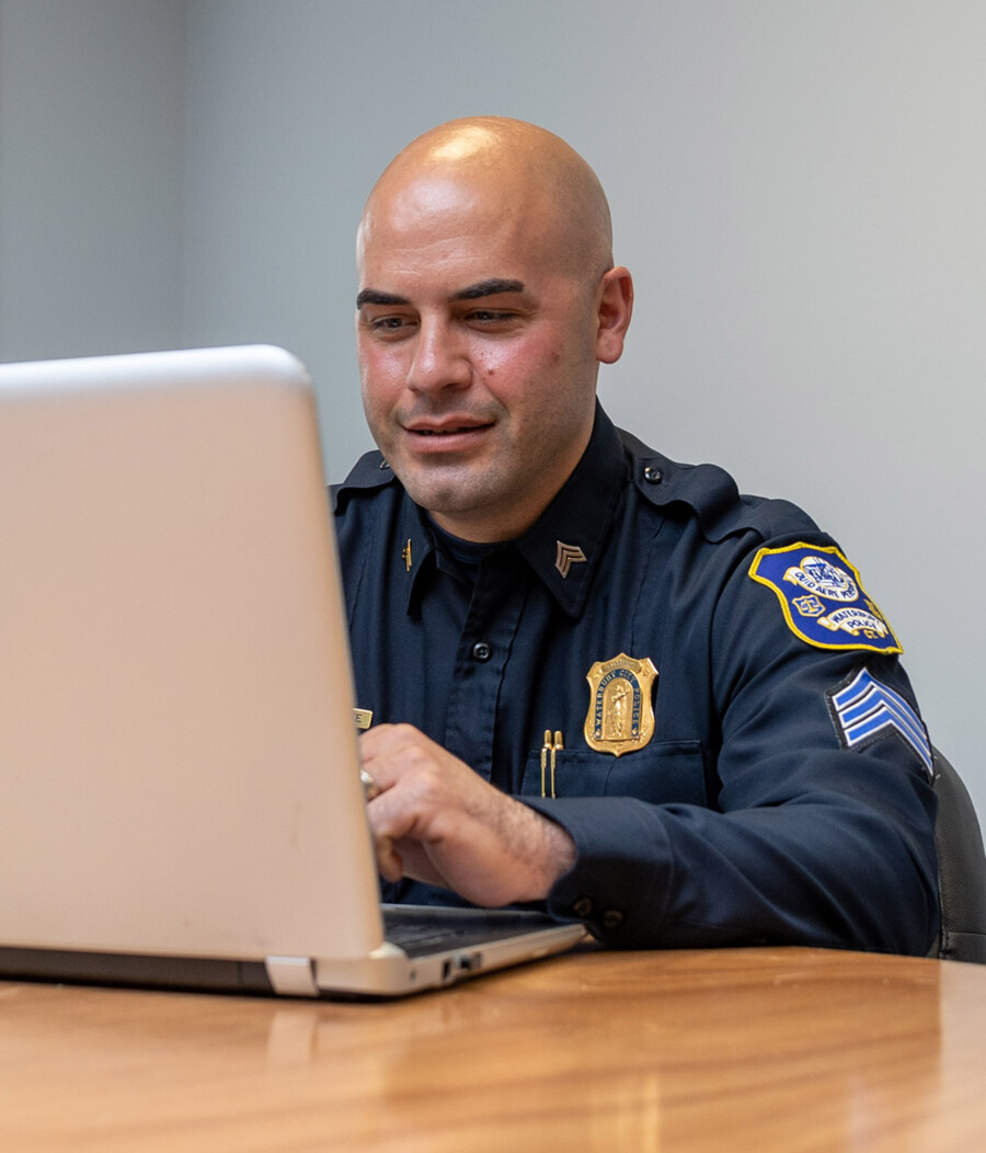 Image of a Waterbury, CT police officer taking an online training course through Post University